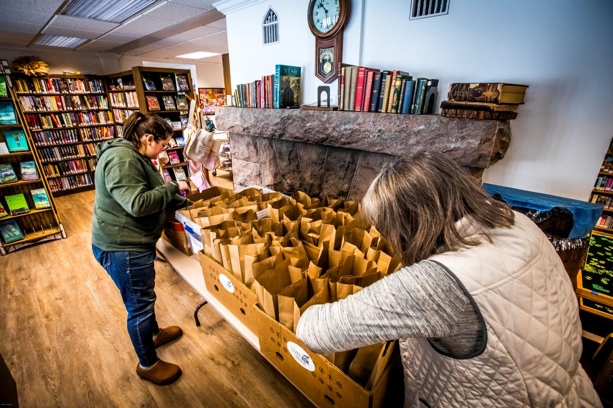 two women in a library packing lunches for delivery to seniors