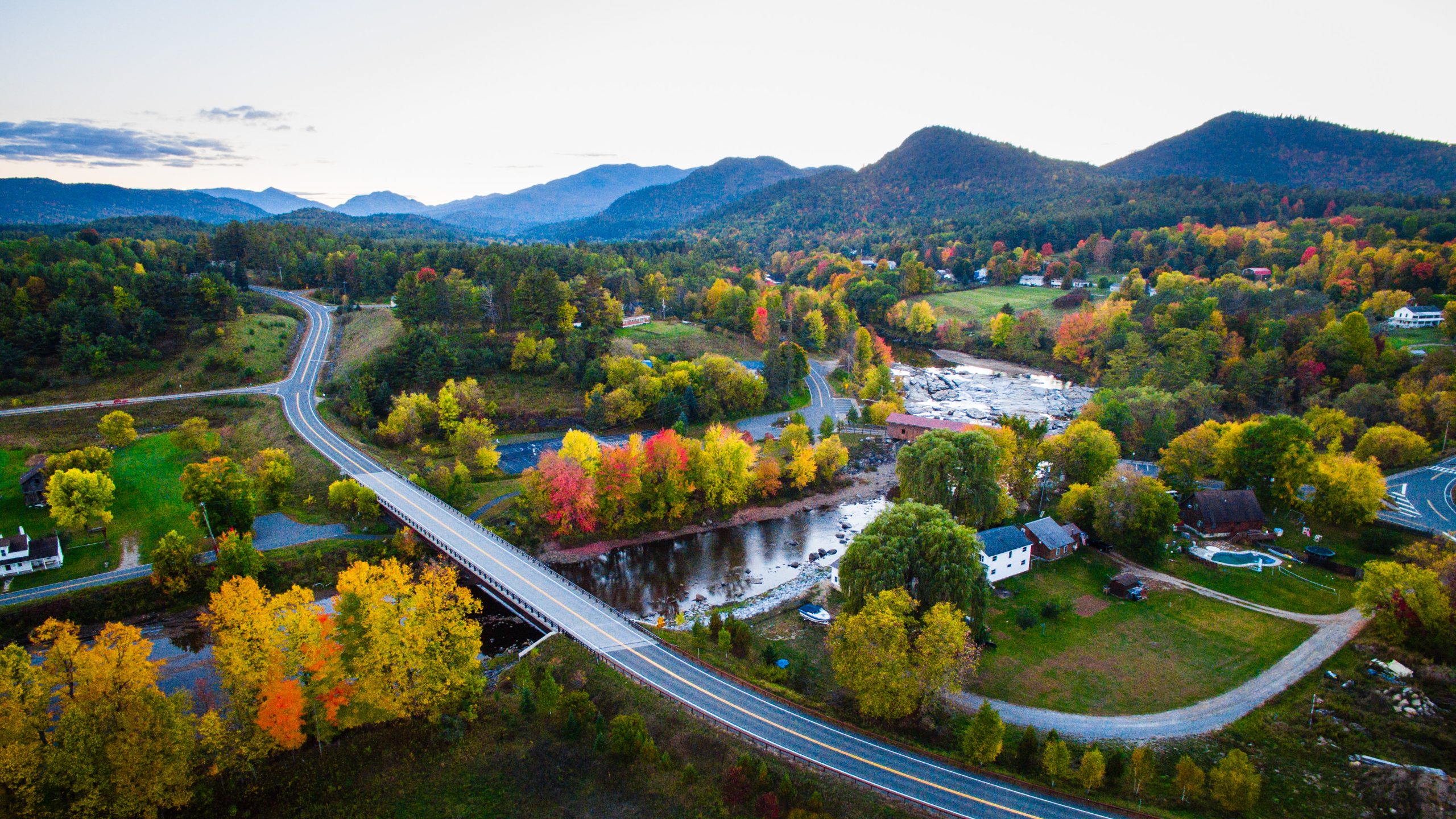 aerial photo of river and road in front of a mountainous horizon