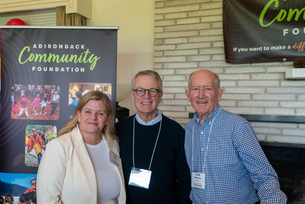 CEO Cali Brooks with board chair and trustee in front of poster