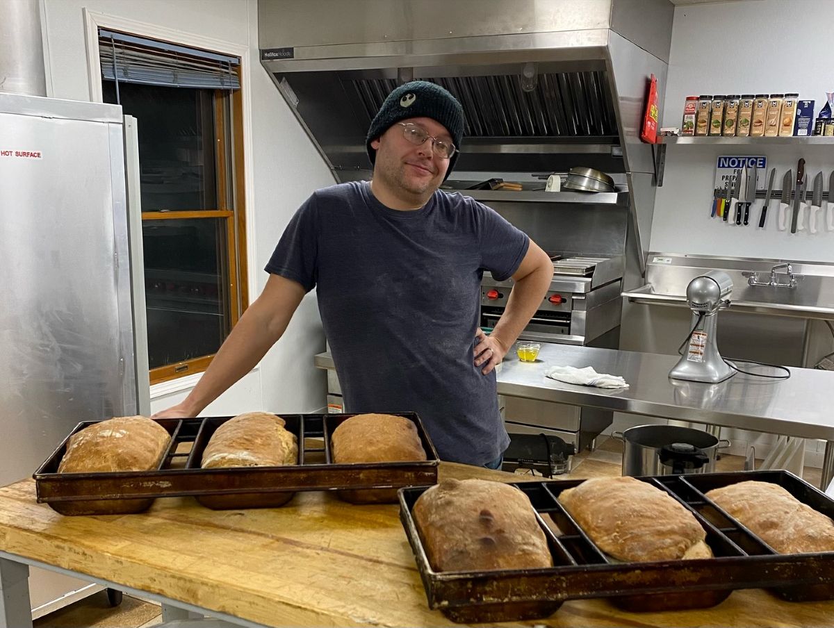 Man stands behind freshly baked bread.