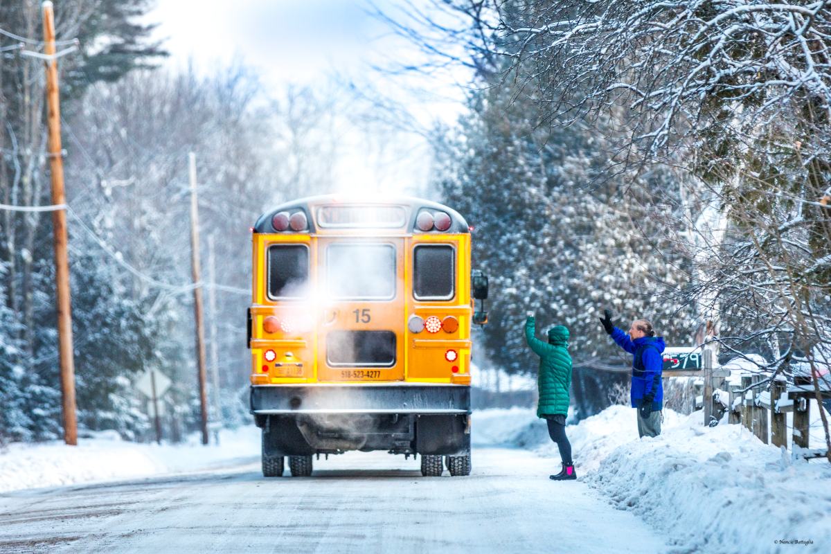 Parents wave their kids off in school bus in the snow
