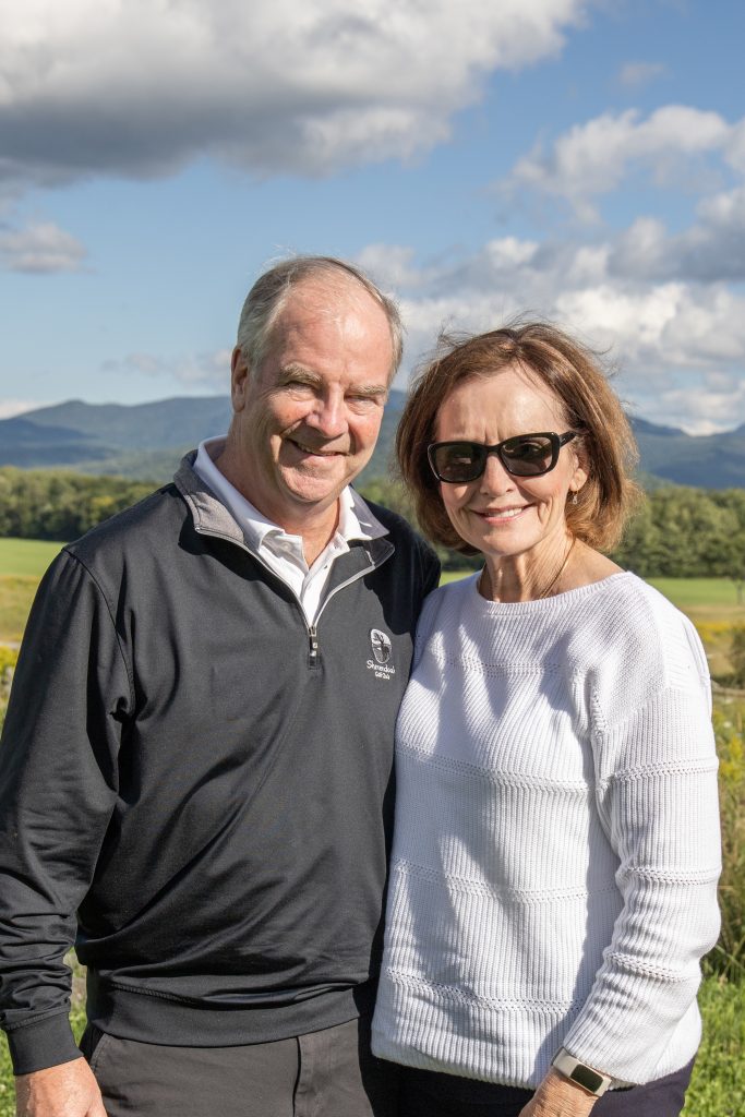 woman and man pose in front of mountains